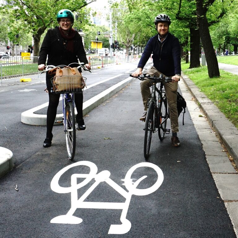 Katherine Copsey MLC and Sam Hibbins MLA sit on bikes in a protected bike lane