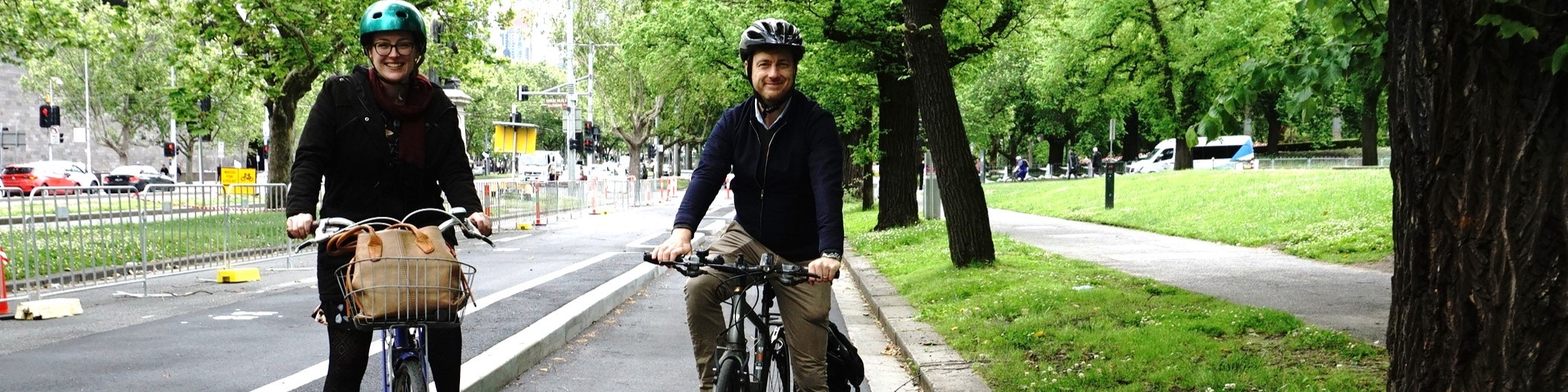 Katherine Copsey MLC and Sam Hibbins MLA sit on bikes in a protected bike lane