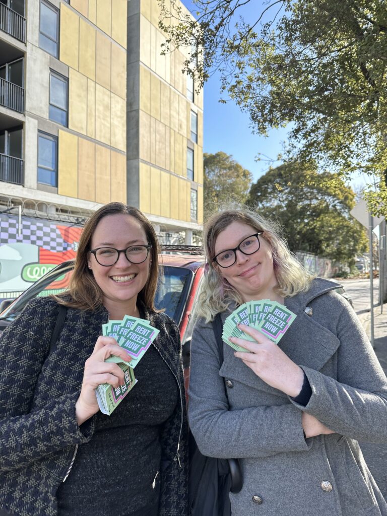 Katherine Copsey MP and a volunteer, holding "Rent Freeze Now" cards while doorknocking.